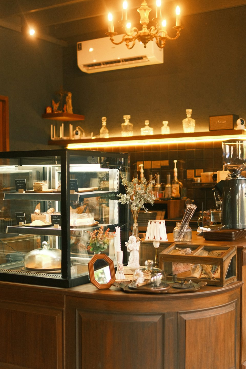 Glass display case filled with cakes and desserts in a cozy cafe.