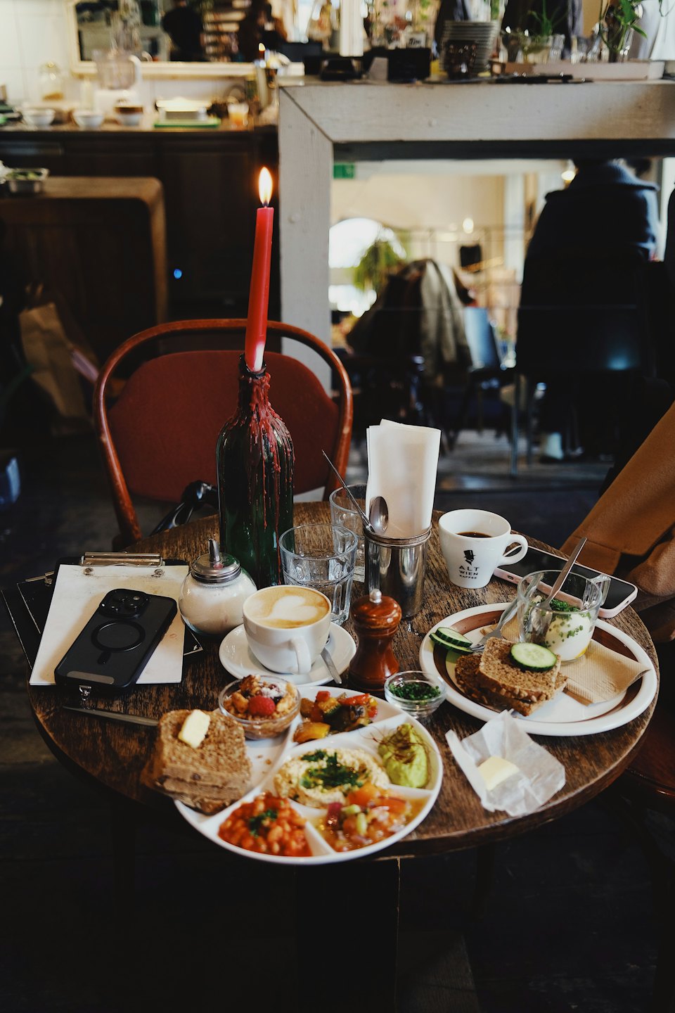 Cafe table with brunch food, coffee, and a red candle.